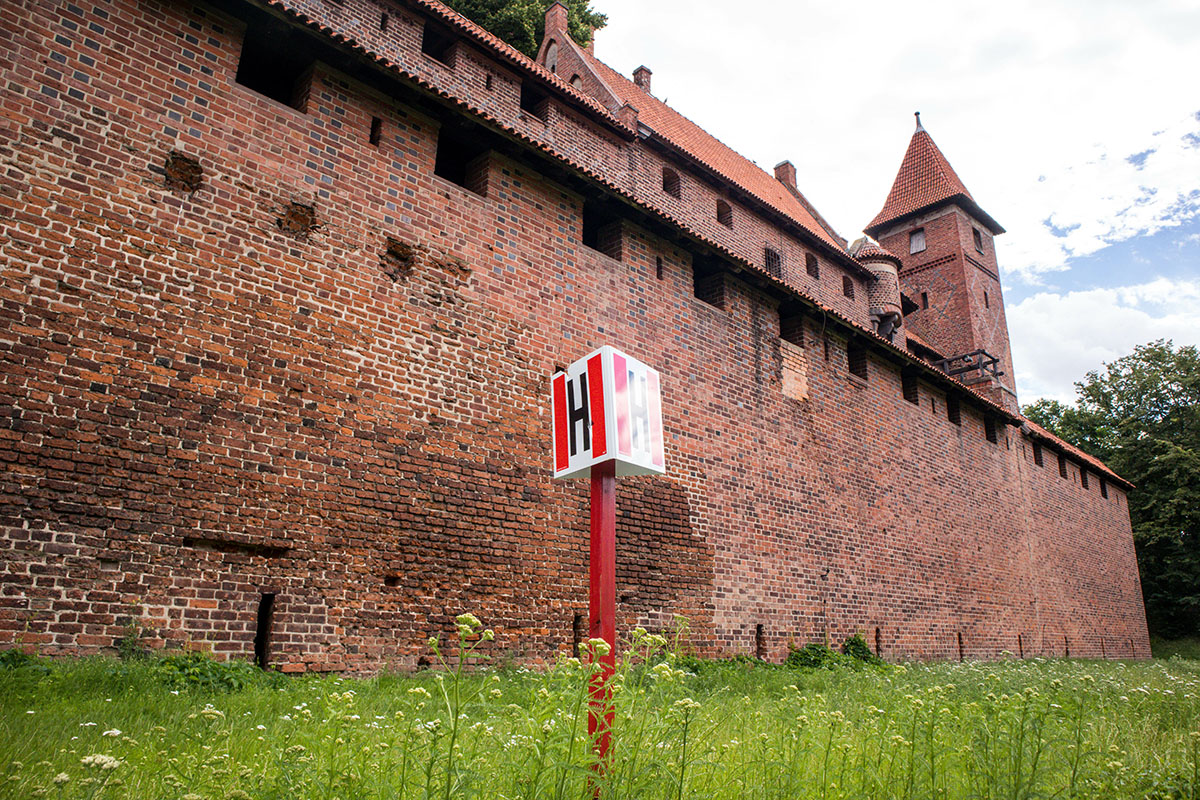 Outside walls and dry moat of Malbork Castle with modern hydrant